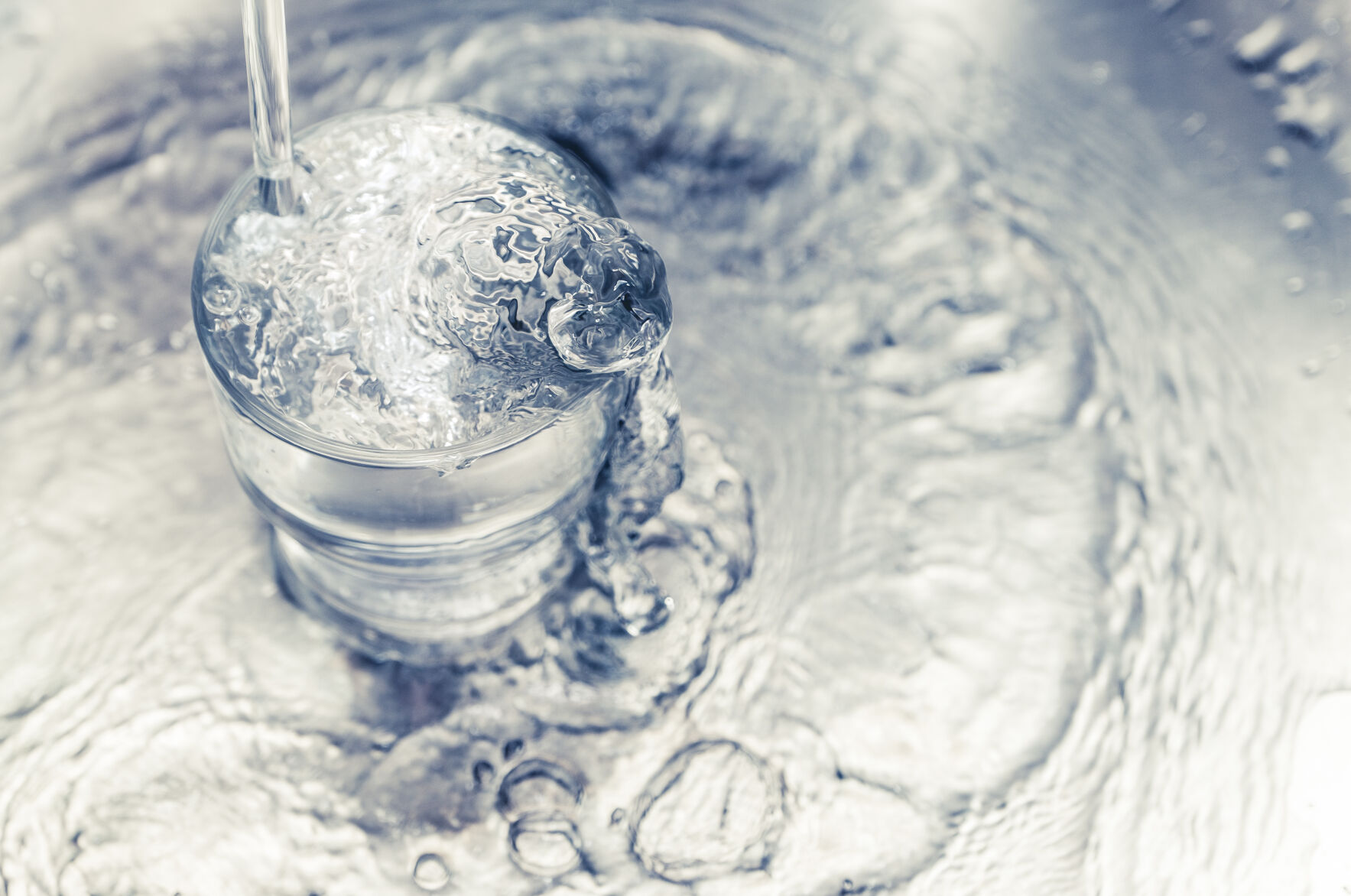 Pouring water from tap to glass on stainless steel