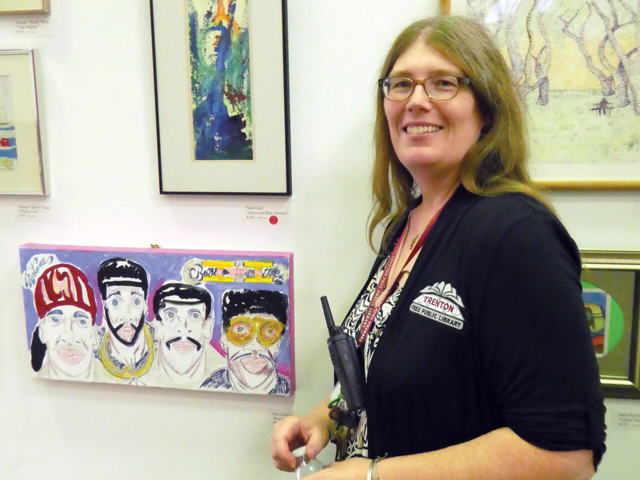 Trenton Public Library coordinator Laura Poll with the library’s new exhibition rotating works by the Trenton A-Team through the end of December