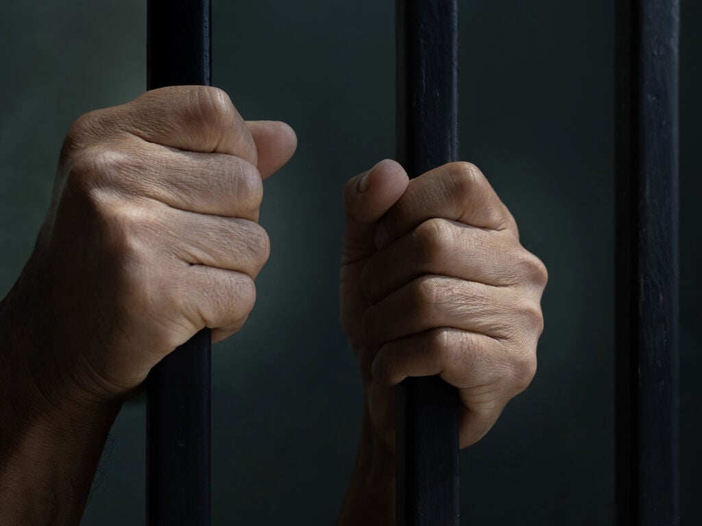 Hands of prisoner behind the cell bars
